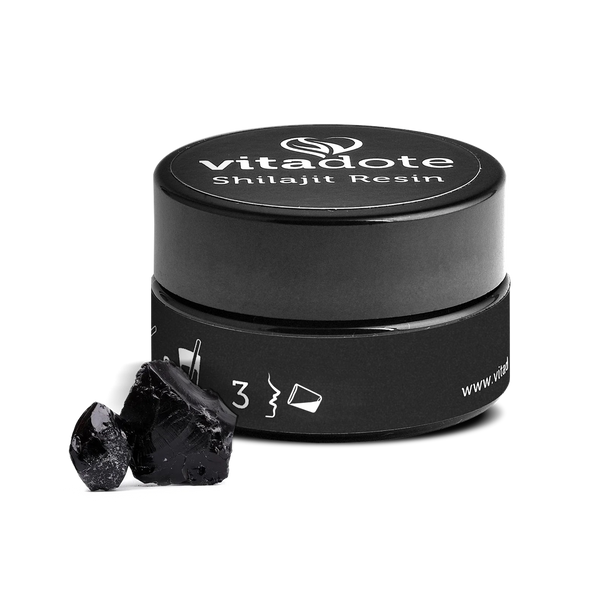 Black container of Vitadote Shilajit Resin with two pieces of black resin on a white background